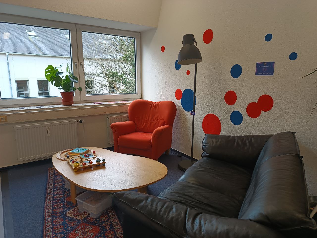 Sofaecke in den Räumlichkeiten der blau:pause Flensburg mit Couch, Sessel und Couchtisch, auf dem Spiele liegen. 