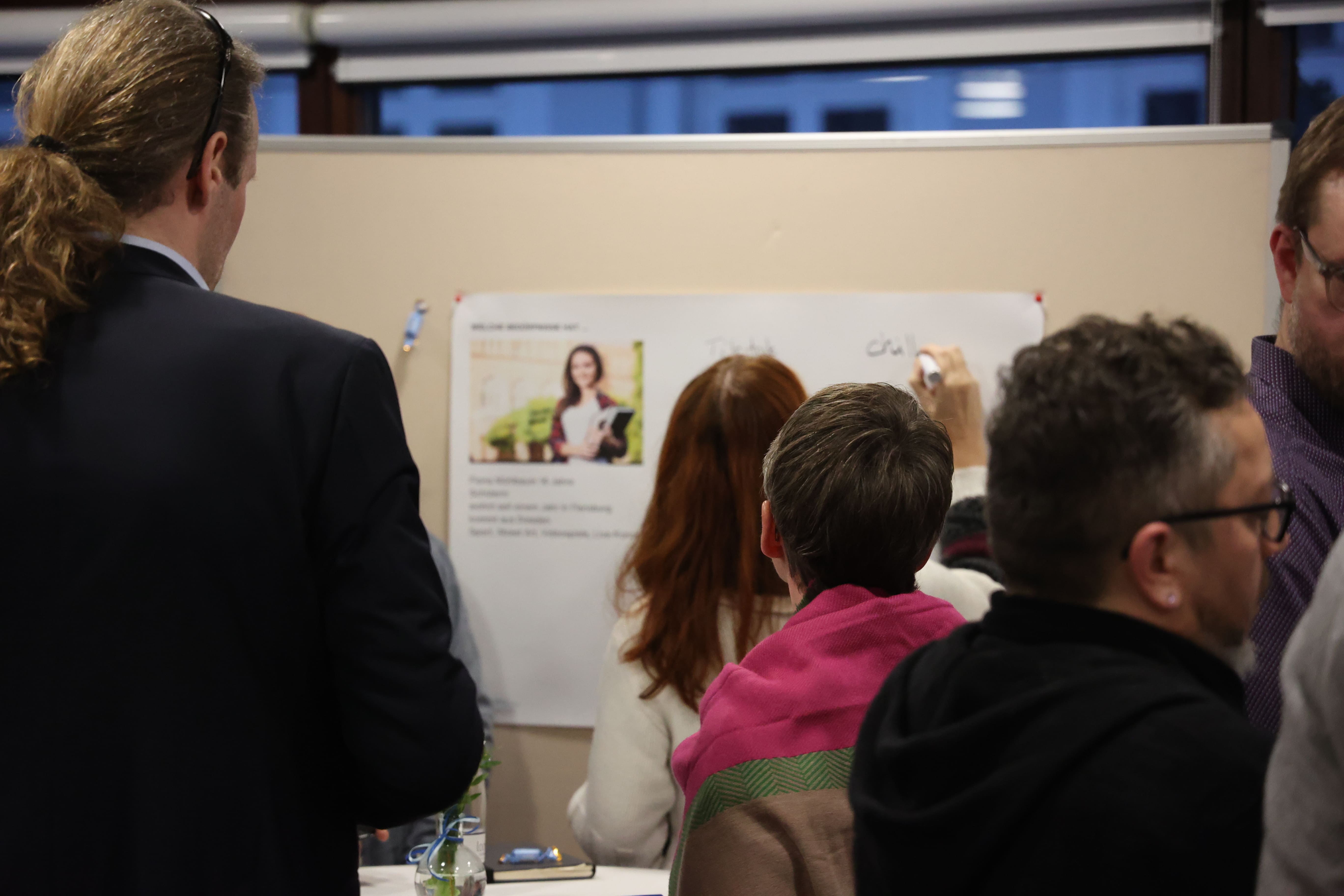 Zum ersten Innenstadtforum Flensburg stehen Menschen in Gruppen vor einer Pinnwand, auf der Ideen gesammelt werden.